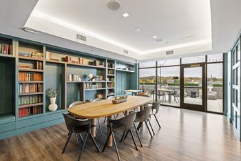 A room with a long table surrounded by chairs and bookshelves filled with books.