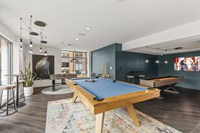 Newton apartment for rent - A pool table is in the middle of a room with a bar stool and a potted plant. at Trio Newton Apartments, Massachusetts