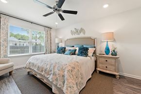 Ocean Springs apartment for rent - Comfortable bedroom with a large bed, blue accents, and a ceiling fan.
