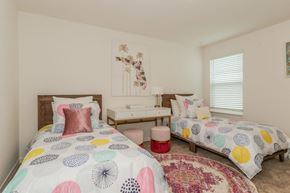 Jacksonville townhouse for rent - Bright primary bedroom with twin beds, desk, and Florida-themed artwork.