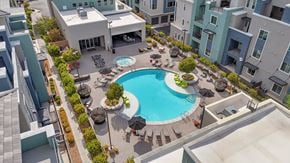 Henderson apartment for rent - A swimming pool surrounded by a patio with chairs and umbrellas.