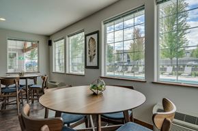 Spokane apartment for rent - Apartments Spokane, WA - Deer Creek - Dining Area With Wood-Look Plank Flooring, Multiple Round Modern Wooden Tables And Chairs, and Large White-Trimmed Windows.