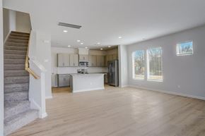Charlotte townhouse for rent - an empty living room and kitchen with a staircase in the background