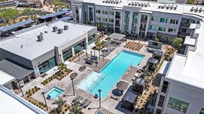 Las Vegas apartment for rent - A large swimming pool is surrounded by lounge chairs and umbrellas.
