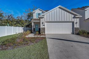 Jacksonville townhouse for rent - Modern two-story house with white vertical siding, turquoise door and shutters, and a white garage door.
