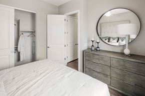 Phoenix apartment for rent - A white bedroom with a round mirror and a dresser.