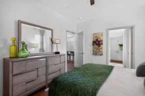 Woodbridge apartment for rent - A bedroom with a large bed and a dresser with a mirror above it.