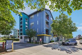 Petaluma apartment for rent - A blue and green building with a parking lot in front.