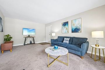 Raleigh apartment for rent - A living room with a blue couch, a coffee table, and a painting on the wall.