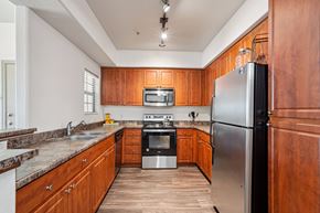 Phoenix apartment for rent - Two-Bedroom Apartments in West Phoenix, AZ - Del Mar Apartments - Kitchen With Warm Wood Cabinetry, Stainless Steel Appliances, Speckled Countertops, Track Lighting, And Wood Style Flooring.