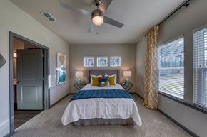 Jacksonville apartment for rent - Spacious primary bedroom with ceiling fan and large windows in luxury Jacksonville apartments near UNF.
