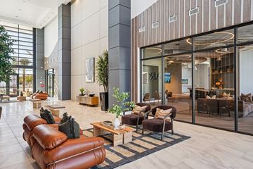 Las Vegas apartment for rent - A modern living room with a brown leather sofa and a glass door leading to a balcony.