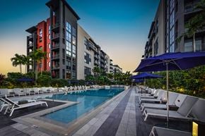 Fort Lauderdale apartment for rent - a swimming pool with chairs and umbrellas in front of some tall buildings
