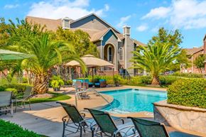 Houston apartment for rent - a swimming pool with chairs and umbrellas in front of a house