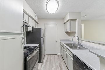 Lawrenceville townhouse for rent - A kitchen with a black fridge and stove top oven.