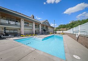 Spokane apartment for rent - A large swimming pool in front of a building with a white fence on the right side.