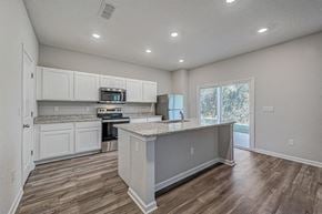 Jacksonville townhouse for rent - Modern kitchen with white cabinets, granite countertops, stainless steel appliances, and a central island.