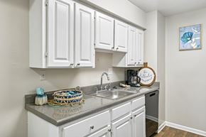 Raleigh apartment for rent - A kitchen with white cabinets and a grey countertop.