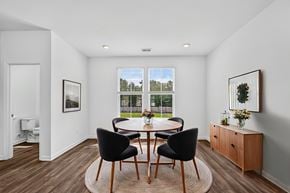 North Charleston apartment for rent - A dining room with a table set for two and a view of a green lawn and trees outside the window.