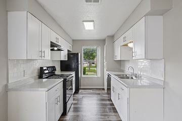 Fort Worth apartment for rent - A kitchen with white cabinets and black appliances.