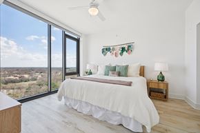 Raleigh apartment for rent - A bedroom with a large bed and a view of the outdoors through the window.