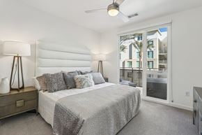 Las Vegas apartment for rent - A bedroom with a large bed and a view of a building outside the window.