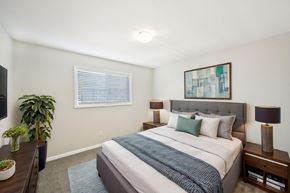 Marietta apartment for rent - Modern bedroom with gray upholstered bed, blue accents, and abstract art.