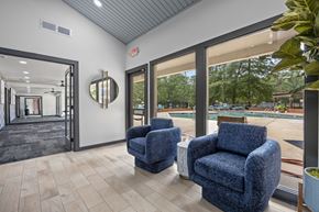 Raleigh apartment for rent - Two blue chairs are placed in a room with a view of a pool and trees outside.