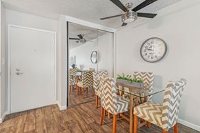 Downey apartment for rent - A dining room with a glass table and chairs with a mirror above it.
