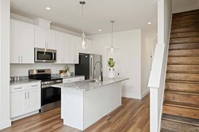 Asheville apartment for rent - View of a kitchen with a white island, granite countertop, stainless steel appliances, and wood flooring.