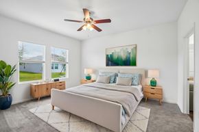 Lakeland apartment for rent - A bedroom with a large bed, a ceiling fan, and a painting on the wall.