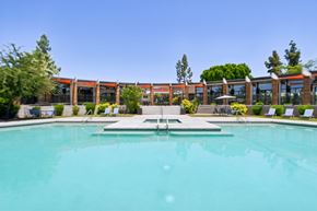 Tempe apartment for rent - A large swimming pool in front of a building with a clear blue sky.