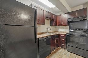 Charlotte apartment for rent - A black refrigerator is in a kitchen with wooden floors.