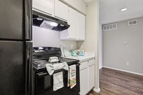 Houston apartment for rent - A kitchen with a black refrigerator and white cabinets.