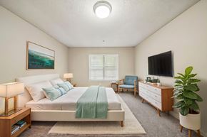 Duluth apartment for rent - A bedroom with a bed, a chair, a dresser, a lamp, a plant, and a painting on the wall.