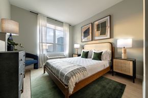 Newark apartment for rent - A bedroom with a large bed, a nightstand, and a window with curtains.