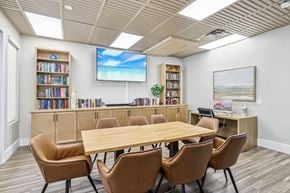 Las Vegas apartment for rent - A conference room with a large table, chairs, and a screen displaying a beach scene.