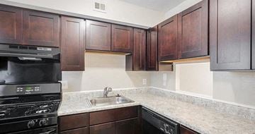Newport News apartment for rent - A kitchen with dark wood cabinets and a black stove.