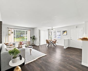 Coeur D Alene apartment for rent - A living room with a grey sofa, a coffee table, a dining table with chairs, and a kitchen area with a countertop.