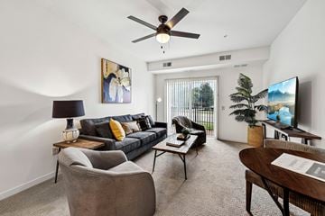 Blaine apartment for rent - A living room with a grey couch, a grey armchair, a wooden coffee table, a ceiling fan, a flat screen TV, and a painting on the wall.