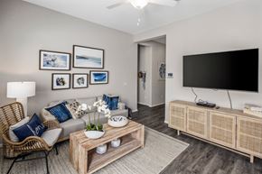 Phoenix apartment for rent - Apartments for Rent in Phoenix AZ - The Crofton at Sheely Farms - Spacious Living Room with a Grey Sofa, Wooden Coffee Table, Armchair, TV Monitor, Mounted TV, and a Ceiling Fan