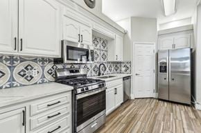 Las Vegas apartment for rent - A kitchen with white cabinets and a black and white tiled backsplash.