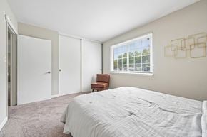 Raleigh apartment for rent - A bedroom with a large bed and a chair by the window.