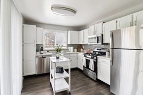 Geneva apartment for rent - Open-concept kitchen with white cabinets and stainless steel fridge at Ashford at Geneva – pet-friendly apartments in Geneva, IL