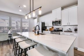 Melissa townhouse for rent - A kitchen with white cabinets and a long island with bar stools.