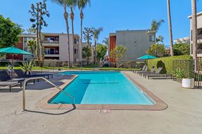 Downey apartment for rent - Apartments for Rent Downey, CA - Park Regency Club Apartments - A Swimming Pool With Pool Deck Lounge Chairs, Shade Umbrellas, Palm Trees, And Surrounding Apartment Buildings.