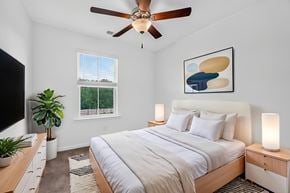 North Charleston apartment for rent - A bedroom with a large bed, a ceiling fan, and a painting on the wall.