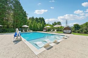Hickory apartment for rent - A large resort-style swimming pool at Hawks Landing in Hickory NC surrounded by trees and lounge chairs