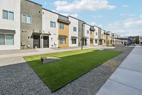 Tolleson apartment for rent - A row of modern townhouses with a grassy area in the foreground.