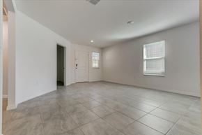 Jacksonville townhouse for rent - Empty living room with gray tile flooring, white walls, front door, and window.